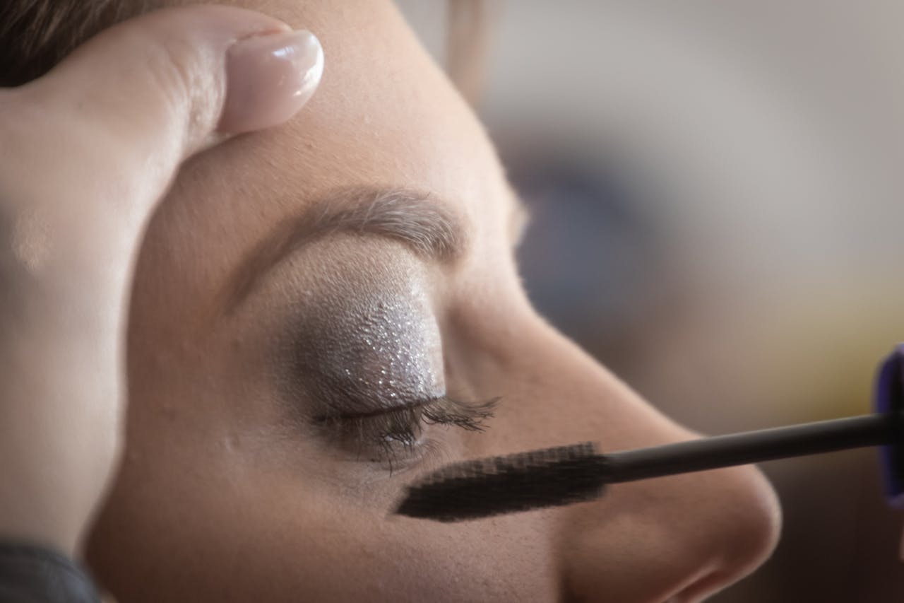 menu-05 A woman's eyelid is delicately painted with glamorous shimmery eyeshadow and mascara.
