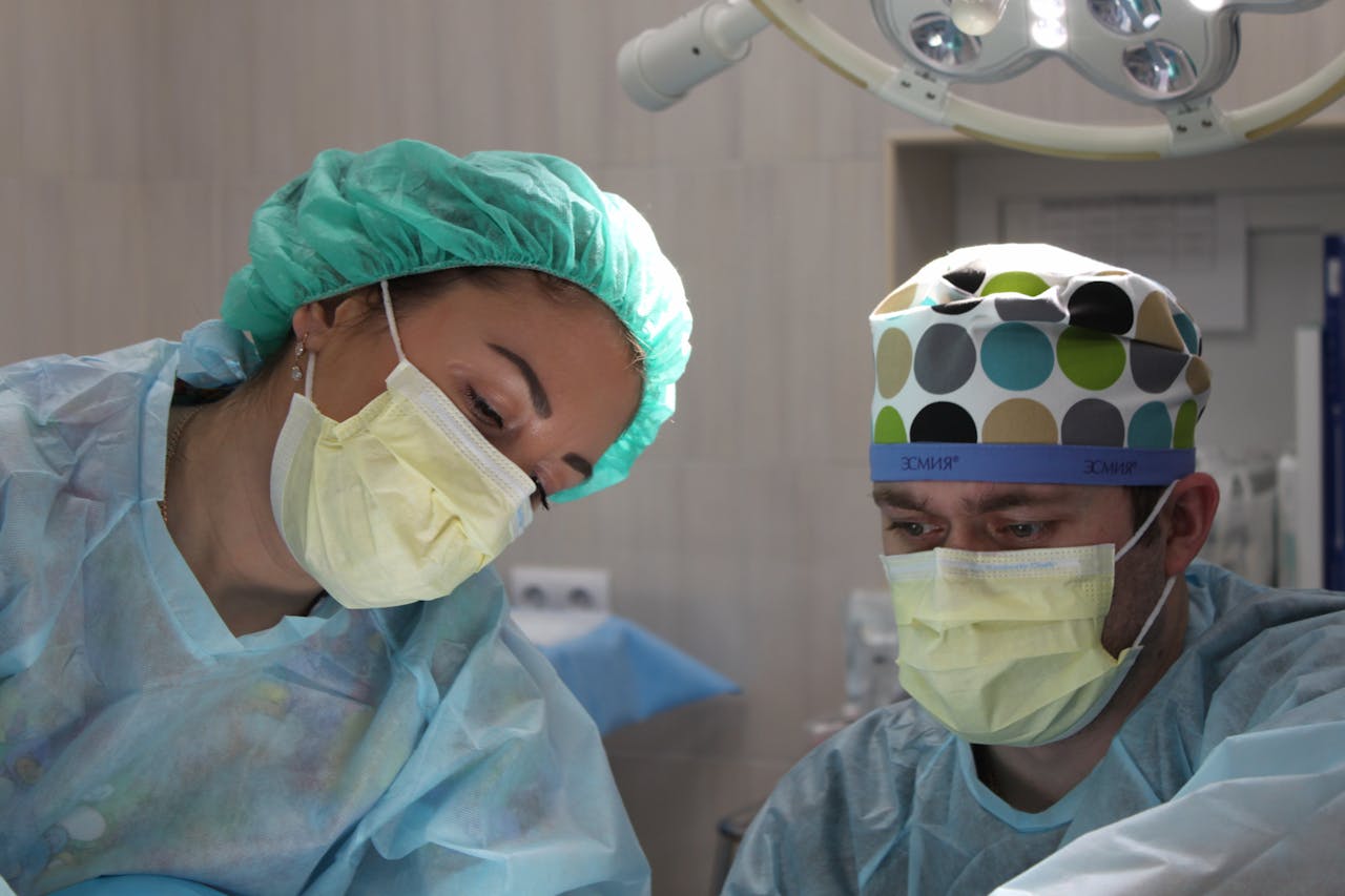 menu-01 Surgeons wearing masks and scrubs conduct an operation in a hospital setting.